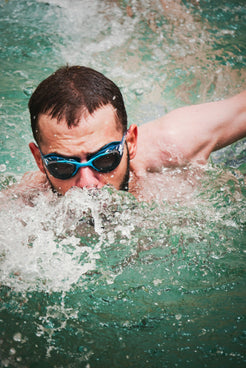 a man swimming in a pool with goggles on