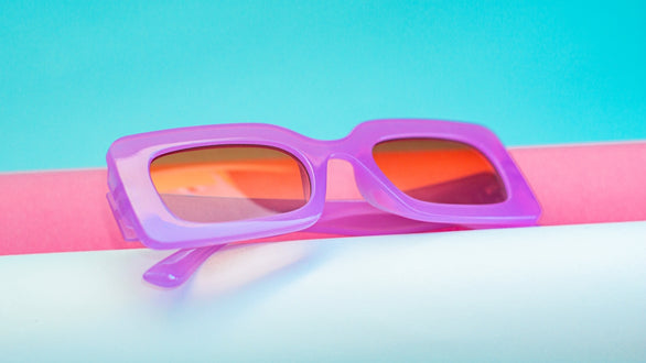 a pair of purple sunglasses sitting on top of a pink and white pole