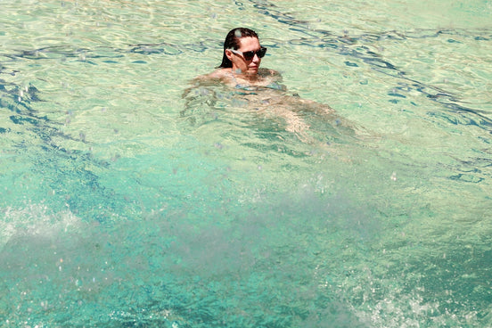 a man swimming in a pool talking on a cell phone