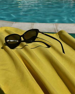 A pair of sunglasses sitting on a towel next to a swimming pool