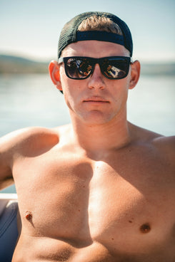 A shirtless man wearing sunglasses and a cap