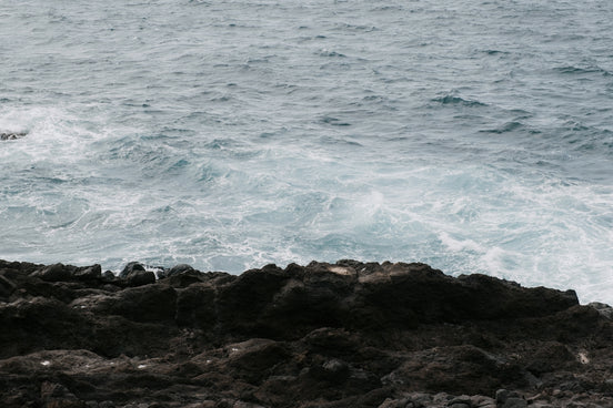 A man standing on top of a rocky beach next to the ocean