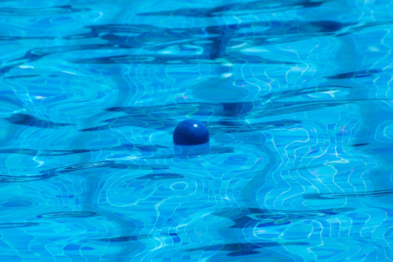 A pool with blue water and a ball in the middle