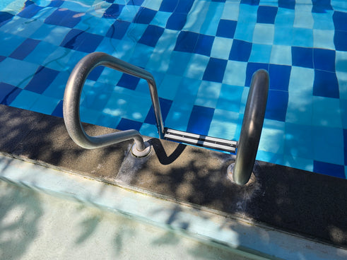 Pool ladder leads into clear blue water.